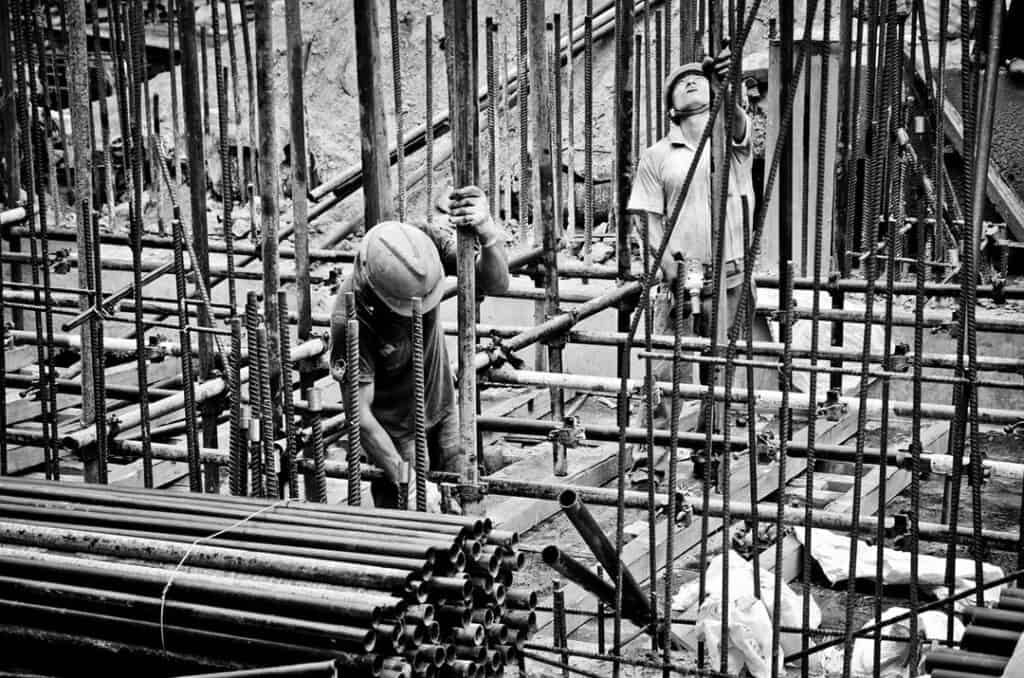 Two person quality checking rebars on construction site